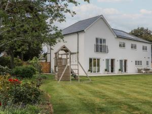 a white house with a playground in the yard at Sea Estate House in Littlehampton