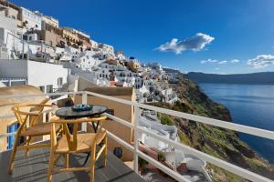 a balcony with chairs and a view of the ocean at VITAMIN STUDIO in Oia