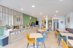 a restaurant with tables and chairs and a cafeteria at Karaez Hôtel - BritHotel Carhaix in Carhaix-Plouguer