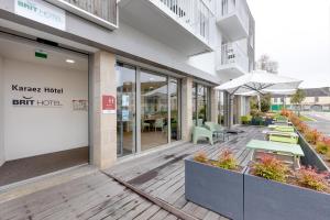 a building with tables and chairs on a wooden deck at Karaez Hôtel - BritHotel Carhaix in Carhaix-Plouguer