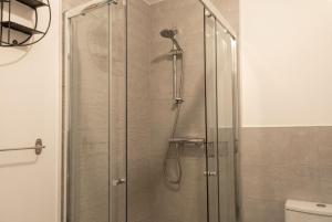 a shower with a glass door in a bathroom at Bright 4 Bedroom Home in Walsall, Free Parking and for EVs in Walsall