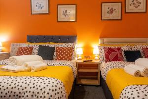 two beds in a room with orange walls at Bright 4 Bedroom Home in Walsall, Free Parking and for EVs in Walsall +33 photos