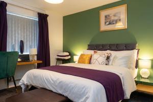 a bedroom with a large bed with a green wall at Bright 4 Bedroom Home in Walsall, Free Parking and for EVs in Walsall