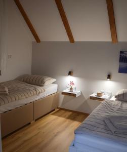 two beds in a room with white walls and wooden floors at Chalet Wörthersee in Velden am Wörthersee