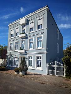 a blue building with white windows on a street at Wilhelms Kojen - Backbordkoje in Wilhelmshaven