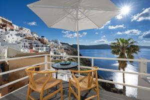 a balcony with a table and chairs and a view of the ocean at VITAMIN STUDIO in Oia