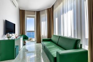 a living room with a green couch and a television at Miramare The Palace Resort in Sanremo