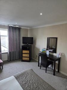 a hotel room with a desk and a television at Wessex Hotel in Street +29 photos
