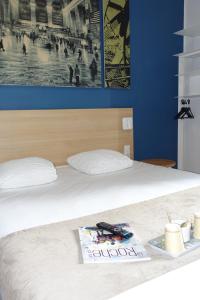 a bed with a plate with a book on it at Hôtel de la Gare - Restaurant Bistro Quai in La Roche-sur-Yon +11 photos