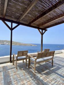 two benches sitting on a patio looking out at the water at Sto Faro - Blue in Kithnos