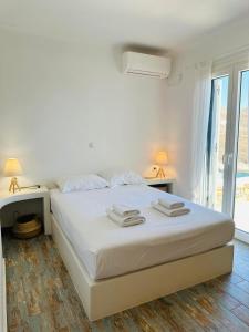a white bedroom with a bed and a window at Sto Faro - Blue in Kithnos