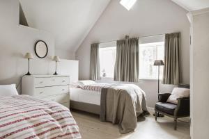 a white bedroom with a bed and a chair at Kleiner Caecilienhof in Pommerby
