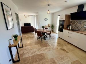 a kitchen and a living room with a table and chairs at Le Clos de L'Oliveraie - Appartements de charme avec piscine proche d'Uzès in Sagriès