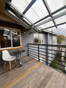 a patio with a table and a chair on a balcony at Hostal Casa Arrayán in Coihaique