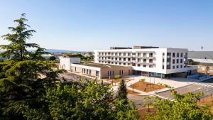 an overhead view of a white building in a city at Parkest Hôtel & Spa in Genas