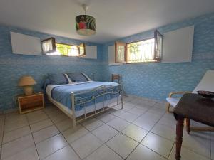 a bedroom with a bed with blue walls and windows at La Chambre du Bout du Monde in Bouillac