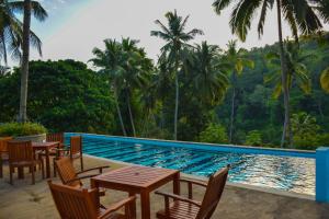 a pool with tables and chairs next to a resort at Athulya Villas, Kandy in Kadugannawa