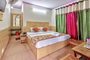 a bedroom with a large bed with colorful curtains at Hotel Moonlight Manali in Manāli