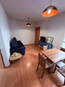 a living room with a table and a blue couch at Espaço inteiro apartamento em Londrina in Londrina