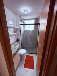 a bathroom with a shower and a toilet with a red rug at Espaço inteiro apartamento em Londrina in Londrina