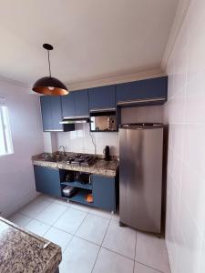 a kitchen with blue cabinets and a stainless steel refrigerator at Espaço inteiro apartamento em Londrina in Londrina