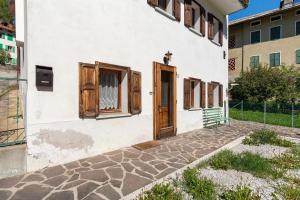 a white building with wooden doors and a sidewalk at Casa Carmen a Vinigo in Vinigo