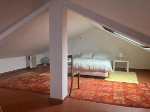 a attic room with a bed and a rug at Cozy Country House near Beaches in Azoia