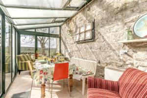 a conservatory with a table and chairs and a stone wall at 2 Bed in Buxton oc-dcbap in Longnor