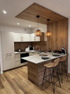 a kitchen with white cabinets and two bar stools at Le Chevalier I - L'Écrin Alsacien in Sélestat