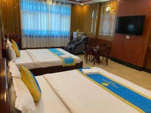 a hotel room with two beds and a flat screen tv at Khách Sạn Sapphire in Gò Công