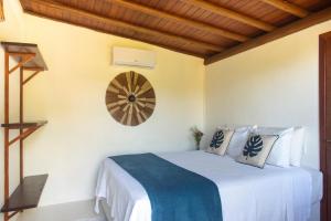 a bedroom with a bed and a clock on the wall at Pousada Lua Cheia Praia do Espelho in Praia do Espelho