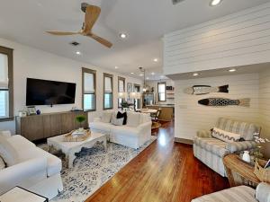 a living room with white furniture and a flat screen tv at The Holland House II in Rosemary Beach
