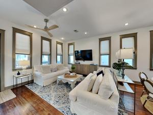 a living room with white furniture and a flat screen tv at The Holland House II in Rosemary Beach