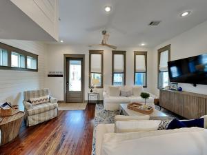 a living room with white furniture and a flat screen tv at The Holland House II in Rosemary Beach