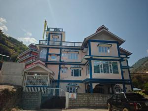 a blue and white house with a car parked in front at Yang home stay in Dirang Dzong