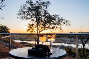 a table with two wine glasses on a balcony at LeoLapa in Hectorspruit