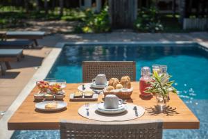 a table with food on it next to a pool at Pousada Lua Cheia Praia do Espelho in Praia do Espelho