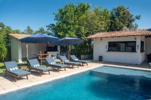 a group of chairs and umbrellas next to a swimming pool at Pousada Lua Cheia Praia do Espelho in Praia do Espelho