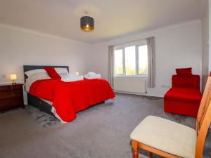 a bedroom with a red bed and a red chair at Tregoning in Lostwithiel