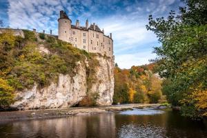a castle on a cliff next to a river at Nid cosy en forêt in Blaimont