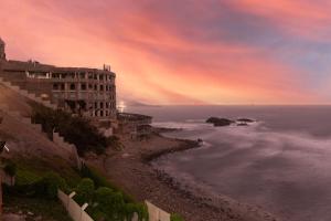 ein Gebäude auf einer Klippe neben dem Meer in der Unterkunft Hotel Sunset Chancay in Chancay