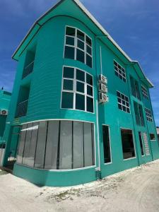 a blue building with large windows on the side of it at Green Villa in Huraa