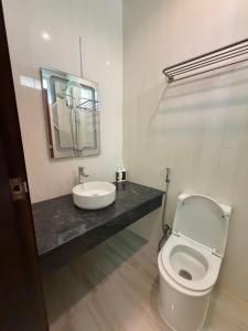 a bathroom with a white toilet and a sink at Green Villa in Huraa