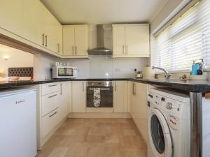 a kitchen with white cabinets and a washer and dryer at Tregoning Annexe in Lostwithiel