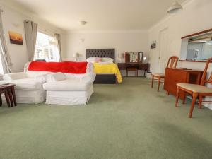 a living room with two white chairs and a bed at Tregoning Annexe in Lostwithiel