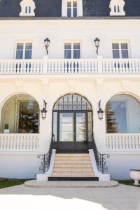 an entrance to a white building with a staircase at DomaineduRocBlanc in Merey