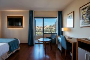 a hotel room with a bed and a desk and a table at Hotel MS Maestranza Málaga Centro in Málaga