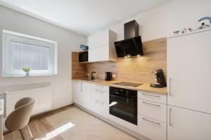 a kitchen with white cabinets and a black oven at Chalet Seewald - Apartment in Seewald +9 photos