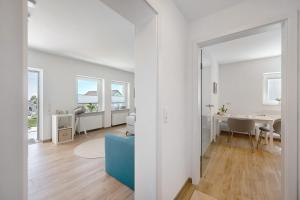 a white living room with a blue couch and a table at Chalet Seewald - Apartment in Seewald