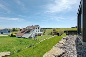 a large white house with a stone wall next to a yard at Chalet Seewald - Apartment in Seewald
